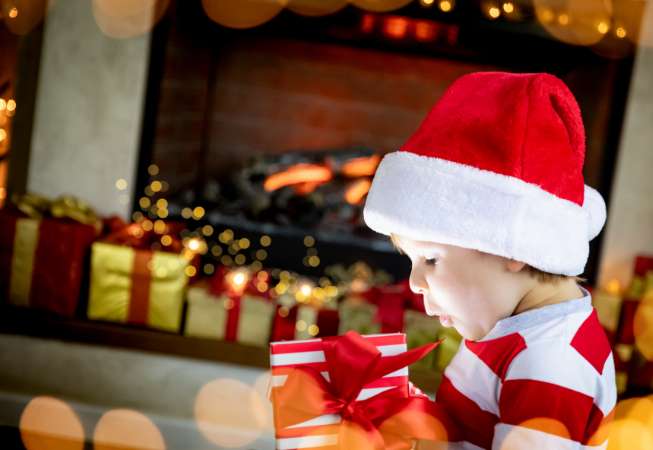 Child in Santa cap opening gift