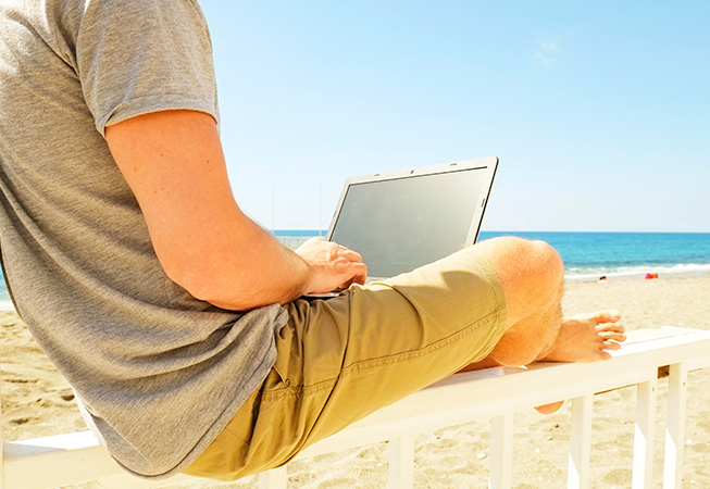 Man at beach working on a laptop