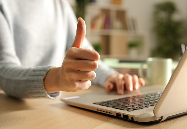 Giving a thumbs-up next to a laptop