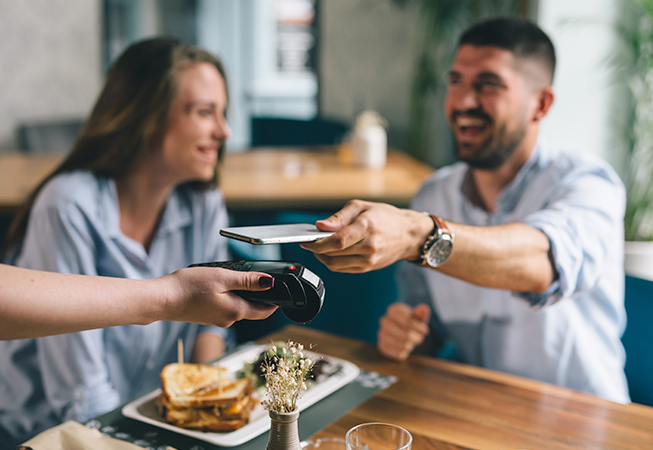 Couple at a restaurant paying with digital wallet