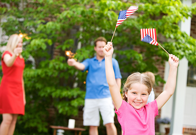 Family in backyard waving small American flags