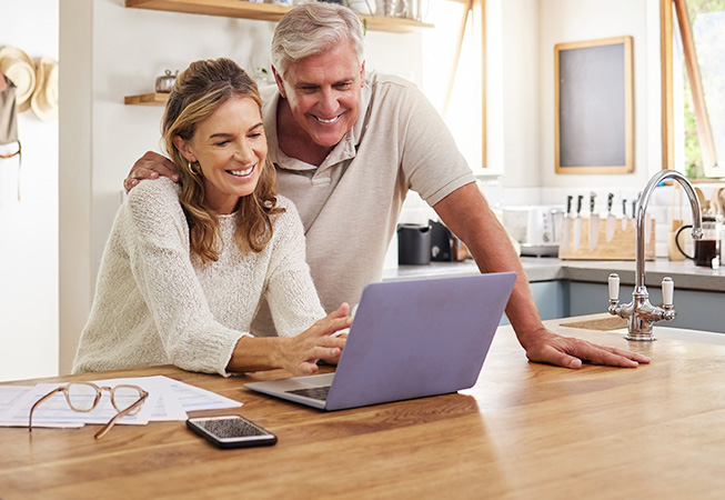 Older couple in kitchen looking at a laptop