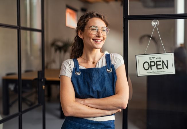 Small business owner next to Open sign